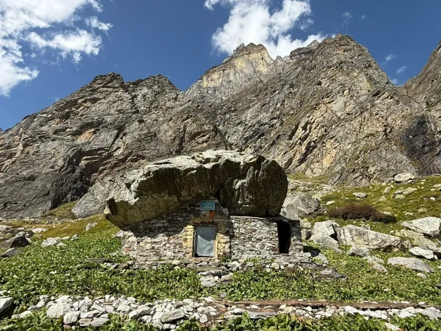 Sri Alakhpuriji's cave: a stone hut built beneath a huge boulder at the foot of rocky Himalayan peaks