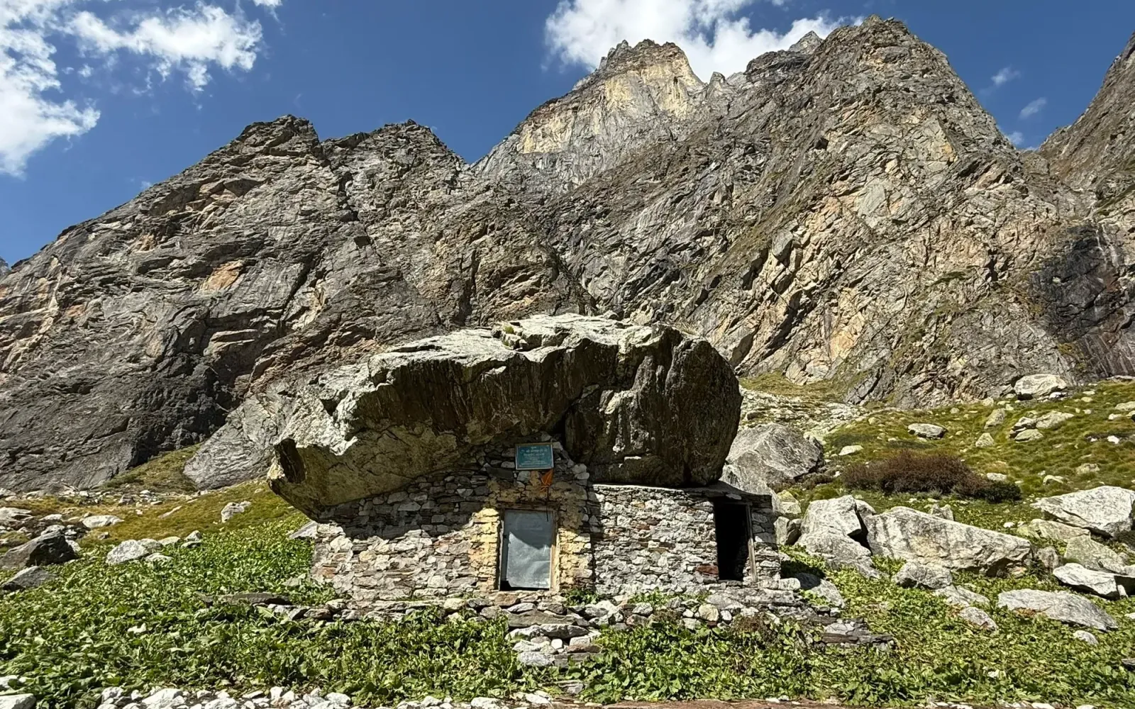 Sri Alakhpuriji's cave: a stone hut built beneath a huge boulder at the foot of rocky Himalayan peaks