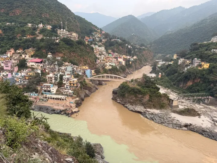 The confluence of the green Bhagirathi and the brown Alaknanda at Devprayag, with houses climbing the hillside