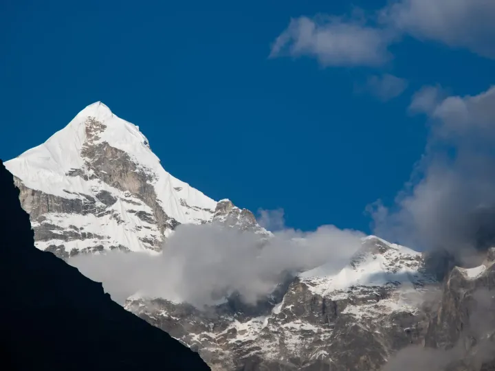 The snow-covered pyramid of Mount Neelkanth against a deep blue sky
