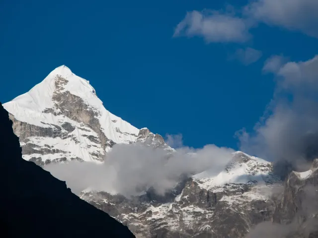The snow-covered pyramid of Mount Neelkanth against a deep blue sky