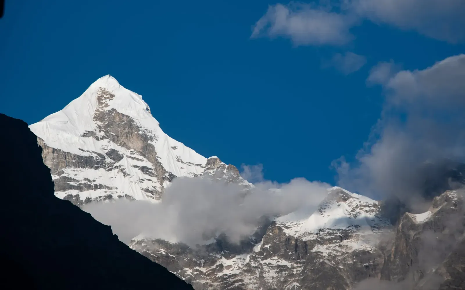 The snow-covered pyramid of Mount Neelkanth against a deep blue sky