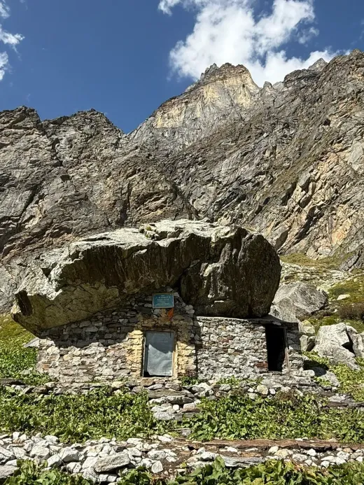 Sri Alakhpuriji's cave: a stone hut built beneath a huge boulder at the foot of rocky Himalayan peaks
