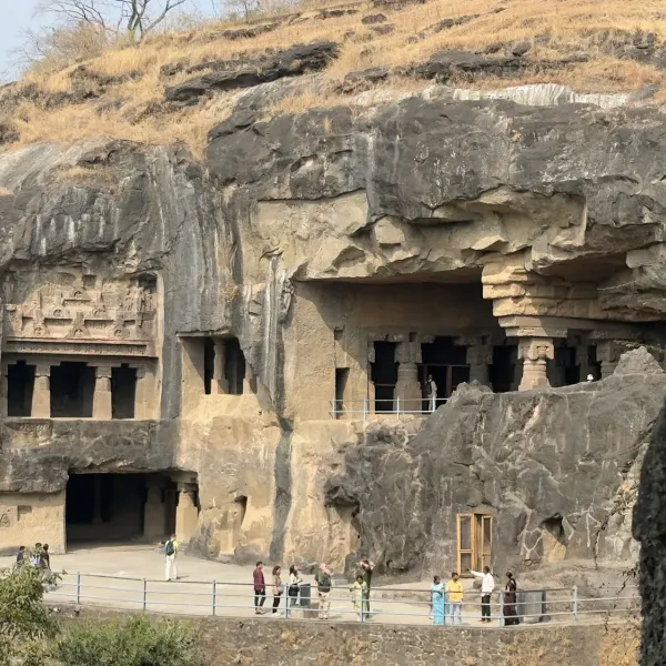 Visitors below the multi-storey rock-cut caves of Ellora